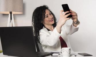 schöne geschäftsfrau, die in ihrem büro sitzt und auf dem handy spricht. Geschäftskonzept foto