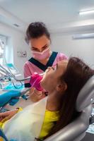 zahnarzt in rosa uniform behandelt die zähne eines patienten