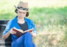 Frau trägt Hut und liest das Buch auf Pickup-Truck foto