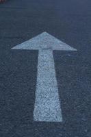 Verkehrszeichen mit weißem Pfeil auf schwarzem Asphalt auf der Straße ist ein geradliniges Symbol, das auf der ganzen Welt verwendet wird. foto