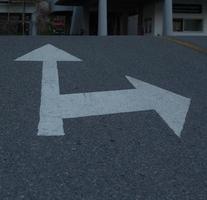 Der weiße Pfeil auf dem schwarzen Asphalt der Straße ist ein einfaches Symbol und die weiße Kurve ist ein Symbol, das auf der ganzen Welt verwendet wird. foto