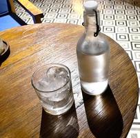 Erfrischender kalter Wodka in der Flasche mit Ice Rocks im Glas serviert im Pub foto