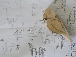 Papageienzeichnung mit Bleistift auf Papier und Holzfigur eines Papageis foto