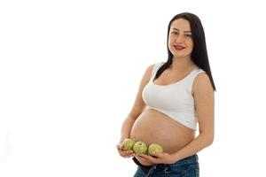 Brünette schwangere zukünftige Mutter mit grünen Äpfeln Hände lächelnd vor der Kamera isoliert auf weißem Hintergrund foto