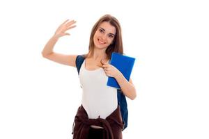 Ein fröhliches junges Mädchen in weißem Hemd hob eine Hand und hält den blauen Ordner in der Hand foto