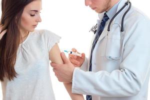 Der Arzt macht eine Injektionsspritze auf der Schulter eines jungen Mädchens in Nahaufnahme foto
