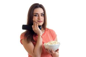 Porträt eines charmanten jungen Mädchens mit Fernbedienung vom Fernseher und Popcorn in der Hand foto