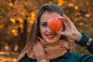 schönes junges Mädchen hält Apfel im Gesicht und lächelt krupnyy Plan an foto