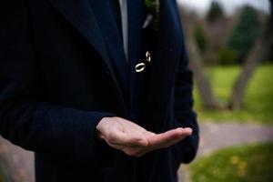 bräutigam, der hochzeitsringe in der hand hält. zwei Eheringe auf dem Boden mit kontrastierenden Eheringen auf dem Boden, auf dem Boden, auf dem Klavier, in der Hand foto