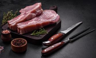 frisches rohes Schweinefleisch auf den Rippen mit Gewürzen und Kräutern auf einem Holzschneidebrett foto