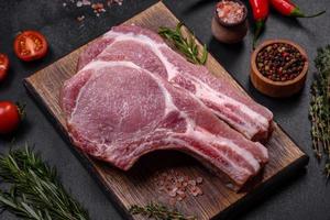 frisches rohes Schweinefleisch auf den Rippen mit Gewürzen und Kräutern auf einem Holzschneidebrett foto