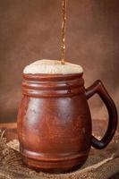 Bierlehm brauner Becher mit Kwas auf einem Holztisch auf dunklem Hintergrund. ein traditionelles Getränk aus Brot, Sauerteig foto