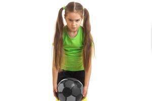Wütendes kleines Mädchen spielt Fußball mit Ball foto