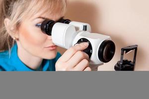 seriöser junger erwachsener Augenarzt bei der Arbeit mit dem Gerät zum Testen des Sehvermögens foto