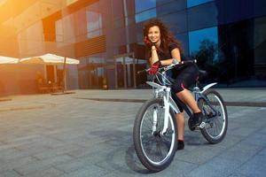 glückliche Brünette trägt Frau auf dem Fahrrad zur Schau foto