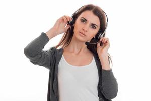 ernsthafte junge brünette Geschäftsfrau mit Kopfhörern und Mikrofon posiert isoliert auf weißem Hintergrund foto