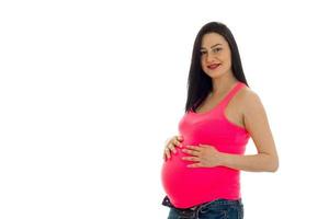 junge schwangere brünette Frau in rosa Hemd posiert isoliert auf weißem Hintergrund foto