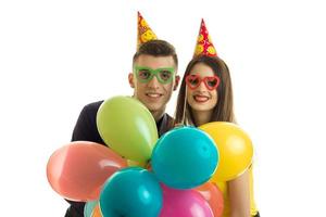 lächelndes schönes junges paar in farbigen gläsern hielt bunte luftballons foto