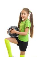 kleines Mädchen in grüner Uniform, das Fußball mit Ball spielt foto