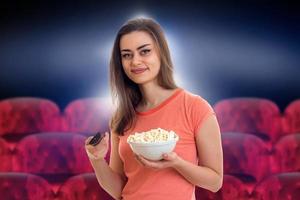 junge Frau mit TV-Fernbedienung und Popcorn foto
