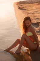 junges sexy Mädchen bei Sonnenuntergang am Strand foto
