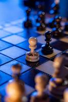 Schachbrett mit Schachfiguren auf blauem Hintergrund. konzept von geschäftsideen und wettbewerbs- und strategieideen. Bauern kämpfen in der Mitte. foto