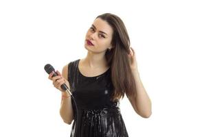 schönes junges Mädchen in schwarz glänzendem Kleid und ein Mikrofon in der Hand foto