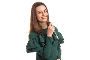 Fröhliche junge Frau in grünem Kleid, die ein Lied mit Karaoke singt foto