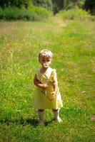 süßes kleines Mädchen in gelbem Kleid, das die Kamera im Garten anschaut foto