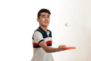 Porträt eines jungen Sportlers, der Tischtennis in Uniform im Studio praktiziert foto
