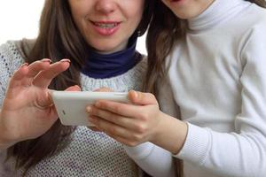 ein nahaufnahmeporträt der hände von müttern mit einem baby, die ins telefon schauen foto