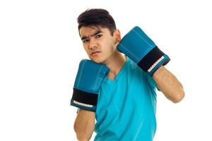 Porträt eines wütenden Kerls, der Boxen in blauen Handschuhen übt, isoliert auf weißem Hintergrund foto