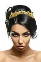 charmantes junges Model mit Krone auf dem Kopf und kreativer schwarzer Frisur foto