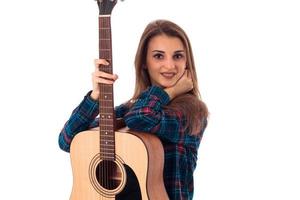 Brunettemädchen mit der Gitarre, welche die Kamera betrachtet foto