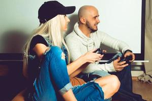 Modisches Paar, das Spaß hat und Computerspiele spielt foto