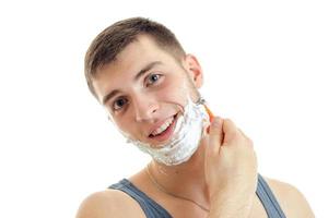 Porträt eines charmanten, fröhlichen Mannes mit Bart, Rasiermesser und Schaum isoliert auf weißem Hintergrund foto