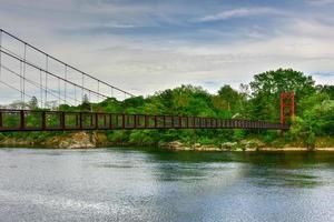 die androscoggin swinging bridge ist eine fußgängerhängebrücke, die den androscoggin river zwischen dem stadtteil topsham heights in topsham, maine, und dem benachbarten brunswick überspannt. foto