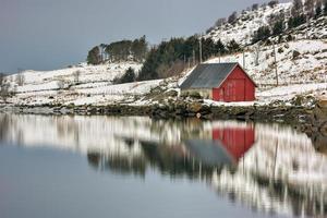 Rorbuer spiegelte sich im Winter an Vagspollen auf den Lofoten, Norwegen, wider. foto