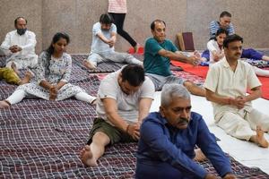 neu-delhi, indien, 19. juni 2022 - gruppen-yoga-übungssitzung für menschen verschiedener altersgruppen im balaji-tempel, vivek vihar, internationaler yoga-tag, große gruppe von erwachsenen, die an yoga-kursen im tempel teilnehmen foto