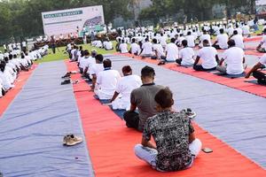 Gruppen-Yoga-Übungssitzung für Menschen verschiedener Altersgruppen im Cricket-Stadion in Delhi am internationalen Yoga-Tag, große Gruppe von Erwachsenen, die an Yoga-Sitzungen teilnehmen foto