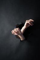 weibliche Hände, auf einem schwarzen, zerrissenen Hintergrund. foto