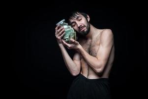 junger Mann mit Geldflasche auf schwarzem Hintergrund foto