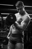 muskulöser Mann mit Hanteln im Fitnessstudio foto