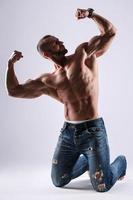 Schöner muskulöser Mann in Jeans, der im Studio posiert foto
