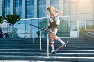 stilvolles Mädchen mit einem Skateboard auf der Straße foto