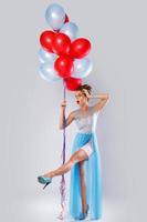 Frau, die ein schönes Kleid mit vielen bunten Luftballons trägt foto