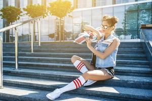 stilvolles Mädchen mit einem Skateboard auf der Straße foto