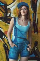 Mädchen in Denim-Overalls posiert mit Graffiti an der Wand foto