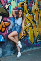 Mädchen in Denim-Overalls posiert mit Graffiti an der Wand foto