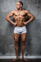 sexy und muskulöser mann, der gegen betonwand aufwirft foto